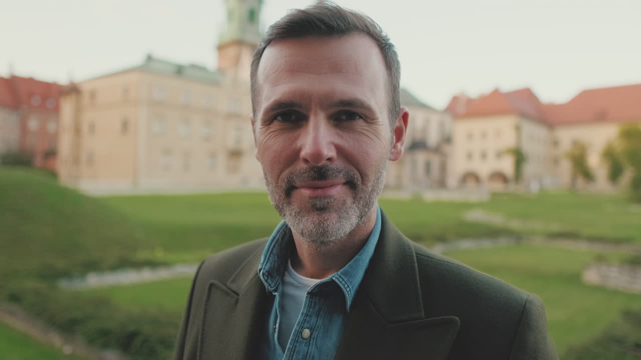 Portrett av en smilende mann med Wawel-slottet i bakgrunnen