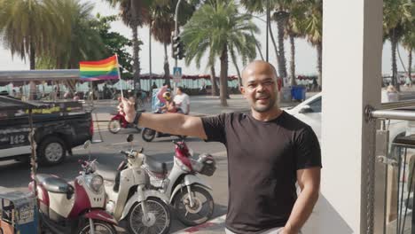 man holding pride flag in a city street