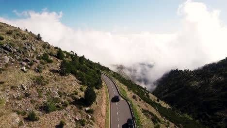 Disparo-De-Drone-De-Un-Auto-En-Movimiento-En-Una-Carretera-Pintoresca-Con-Curvas,-Inversión-En-Un-Día-Soleado,-Drone-De-Madeira