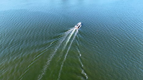 motor boat floating slowly by the waterscape. water vehicle leaving the white traces on the surface. aerial view.