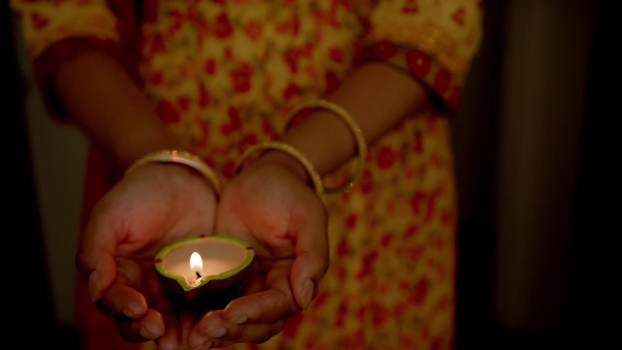 Holding lit diya, Indian woman in traditional sari celebrating festival with joy