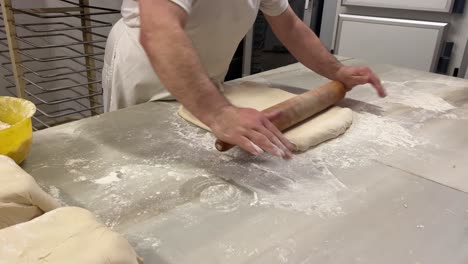 artisan baker rolling out pastry puff in his workshop