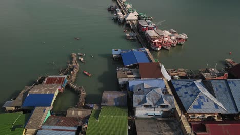 Toma-Aérea-Inclinada-Hacia-Arriba-Siguiendo-El-Muelle-De-Pesca-De-Madera-Bang-Bao-A-Lo-Largo-De-La-Costa-De-Koh-Chang,-Tailandia