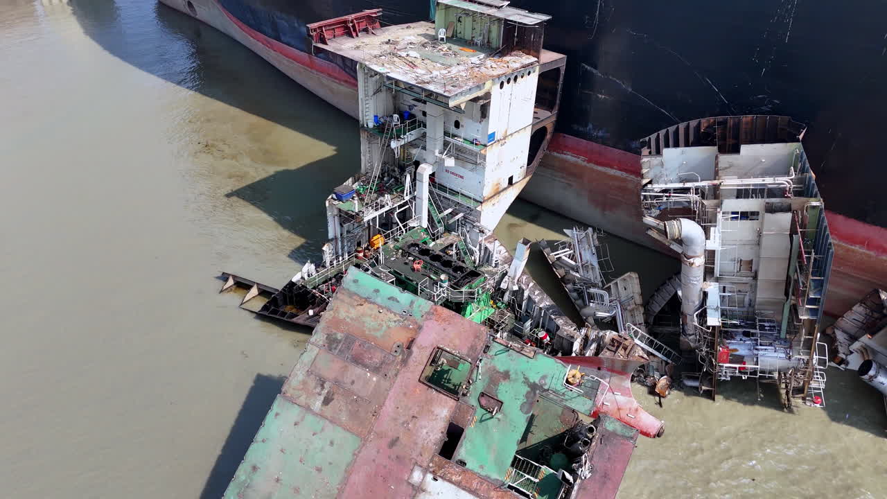 Cinematic panning aerial shot of large wreckage beside an abandoned cargo ship in Bangladesh