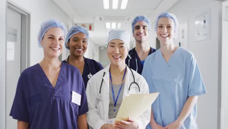 video de un grupo diverso de trabajadores médicos felices con gorras quirúrgicas sonriendo en el pasillo del hospital