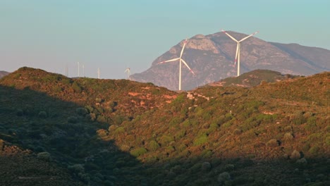 Quickly-rotating-wind-power-turbines-in-setting-of-sunlit-hill-valley-of-Aegean-Turkey-at-sunset