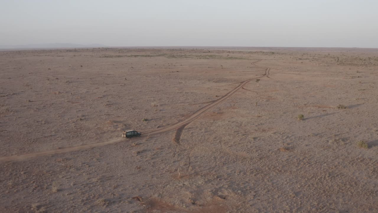 aerial footage of vehicle cruising through stunning Loisaba Conservancy's diverse terrain—lush grasslands, winding rivers, and wildlife roaming freely