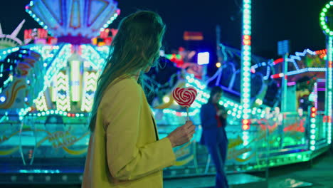 romantic girl going illuminated luna park. smiling woman with lollipop funfair.