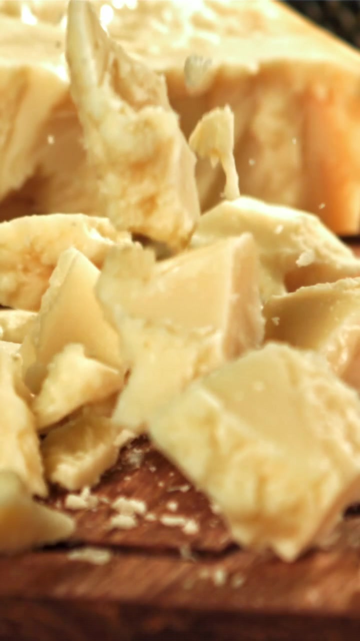Morceaux de parmesan tombant au ralenti sur une planche en bois