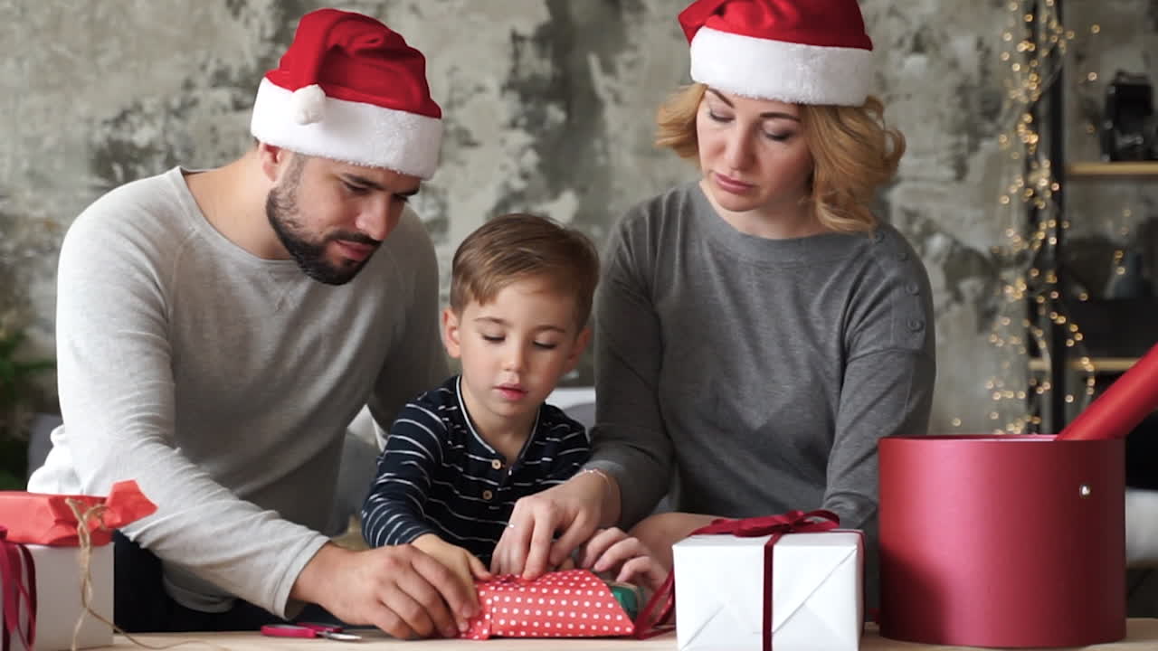 madre, padre e hijo pequeño preparan regalos de navidad