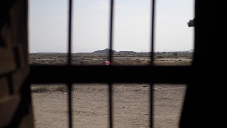 mirando a través de las barras de metal de la ventana hacia el árido paisaje rural en gwadar