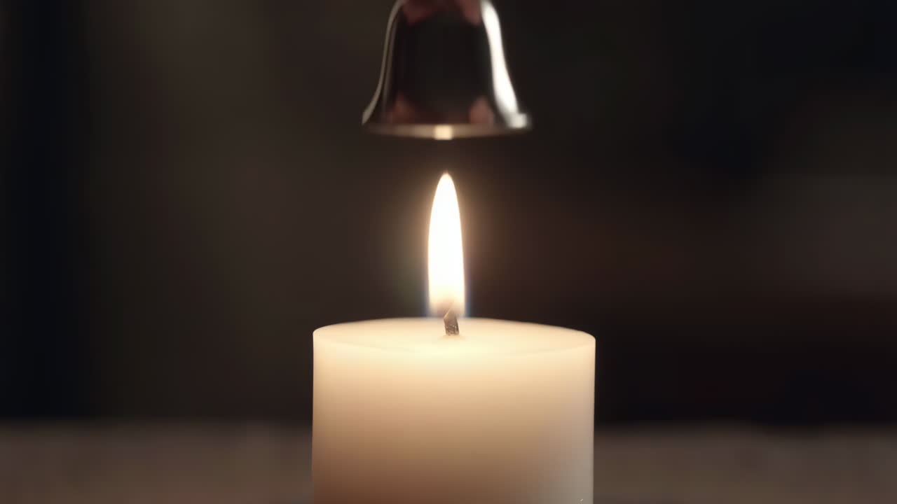 Ruka používající zhášedlo k uhašení plamene svíčky