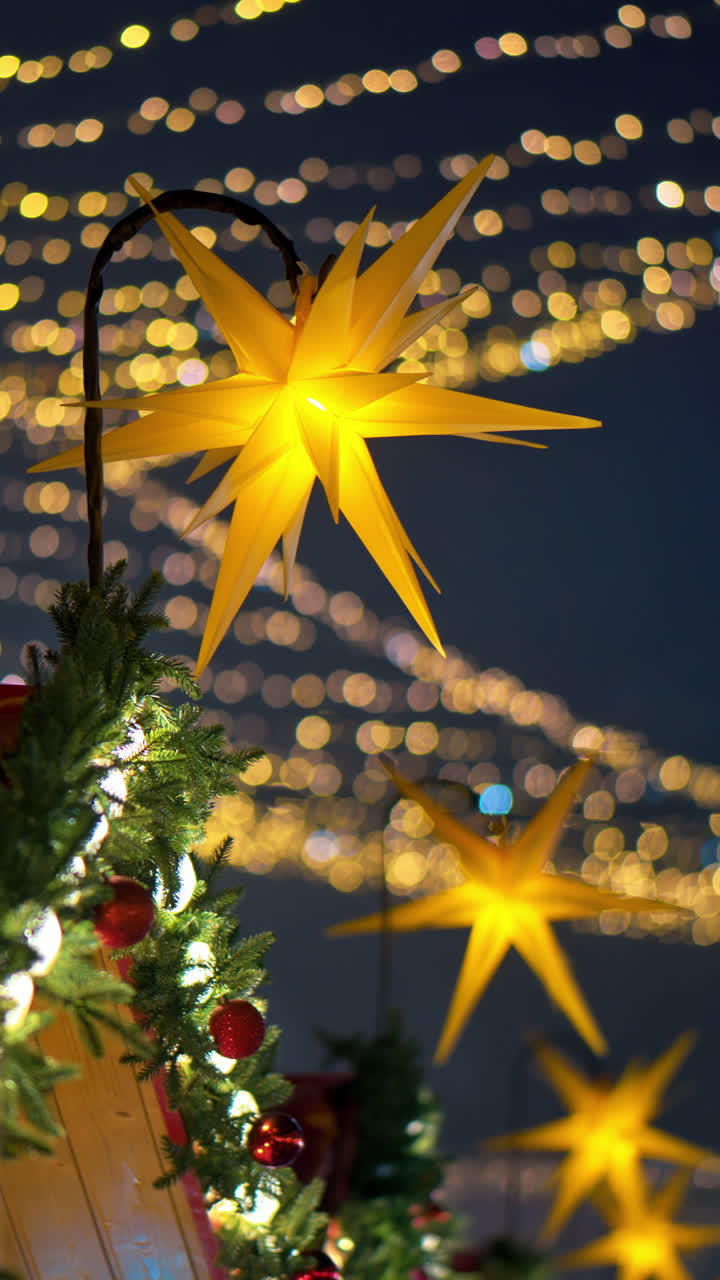 Close up of a Christmas garland on a market boutique with blurry lights on the background. Vertical
