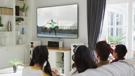 행복 한 가족 이 집 에서 함께 앉아서 tv 에서 육상 자벨린 대회 를 시청 하고 있다