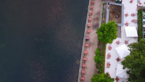 Jardín-De-Cerveza-En-El-Lago,-Sombrillas-Blancas-Increíble-Vista-Aérea-Vuelo-A-Vista-De-Pájaro-Imágenes-De-Drones-Del-Lago-Schlachtensee-Berlin-Golden-Summer-Sunset-2022-4k-Vista-Cinematográfica-Desde-Arriba-Por-Philipp-Marnitz