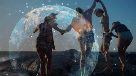 animación de una red global brillante sobre amigas tomadas de la mano caminando por la playa al atardecer