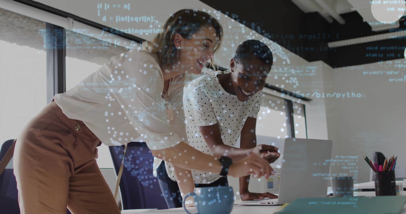 Two software engineers leaning over desk pointing code on laptop then reviewing and testing changes