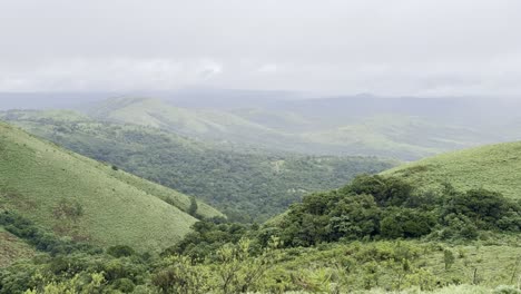 rolling green mountains of devarmane, malnad, karnataka during monsoon. rain clouds sweep swiftly overhead, capturing the serene and dramatic beauty of the western ghats