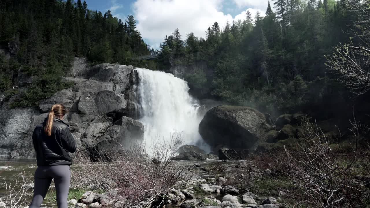 vista trasera de una turista parada frente a la cascada de chute neigette en rimouski, quebec, canadá - plano general