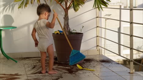 Joven-Niño-Latino-Barriendo-La-Suciedad-Del-Suelo-Después-De-Ensuciarlo-Con-Suciedad-De-Una-Maceta