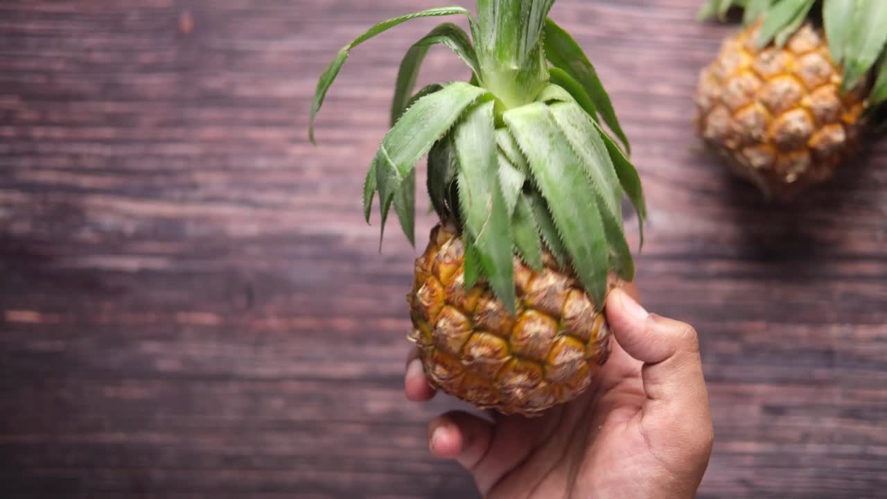 나무 표면 에 파인애플 을 들고 있는 손