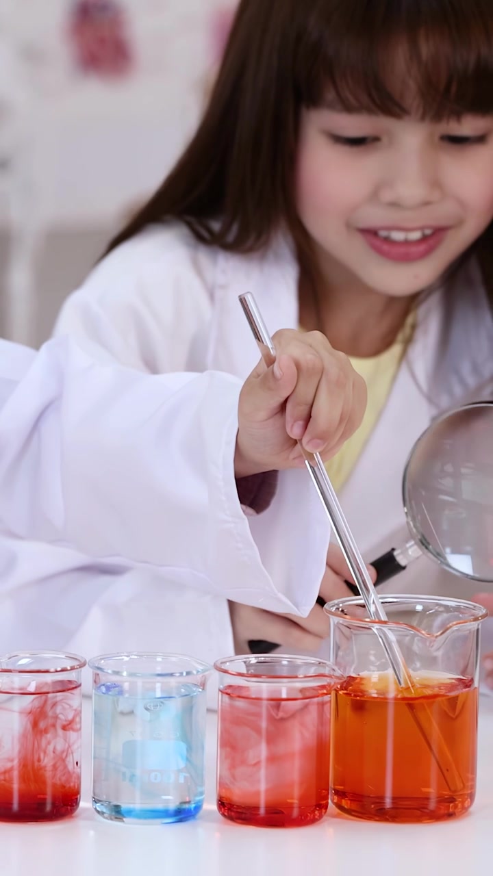Nuori tyttö tekemässä tiedekoetta värikkäillä nesteillä laboratoriossa
