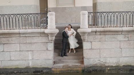 couple posing on stone steps by canal