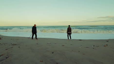 silhouette of two men observing the afternoon ocean panorama with high waves