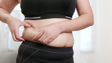 close-up of a young woman touching and worry her belly overweight diet and weight loss