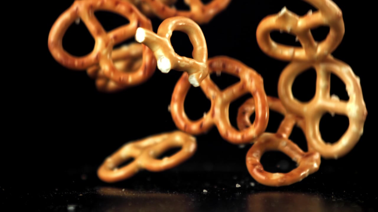 Pretzel salati che cadono in super slow motion su uno sfondo nero.