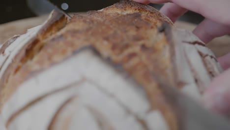 close-up rack focus of a knife cutting through a loaf of artisan bread