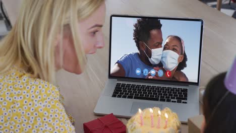caucasian mother and daughter celebrating birthday while having a video call on laptop at home