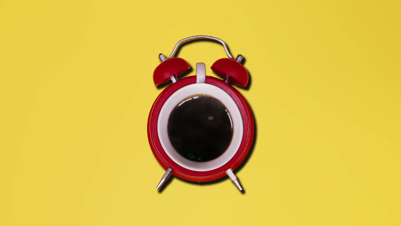 노란색 배경 위에  ⁇ 은 알람 시계 안에 있는 어두운 갈색 뜨거운 커피 한 잔