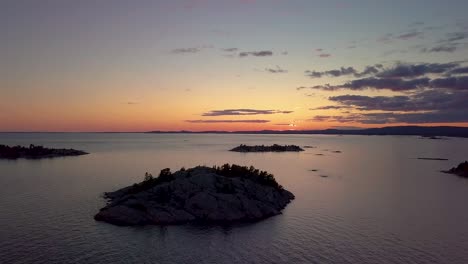 rocky pine tree islands in big lake just after sunset, drone aerial wide dolly in