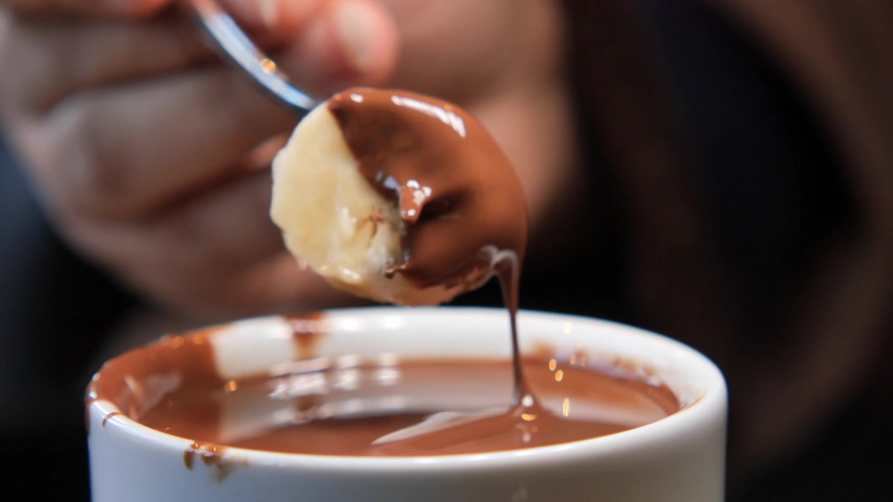 Primo piano di una fetta di banana immersa nel cioccolato fuso.