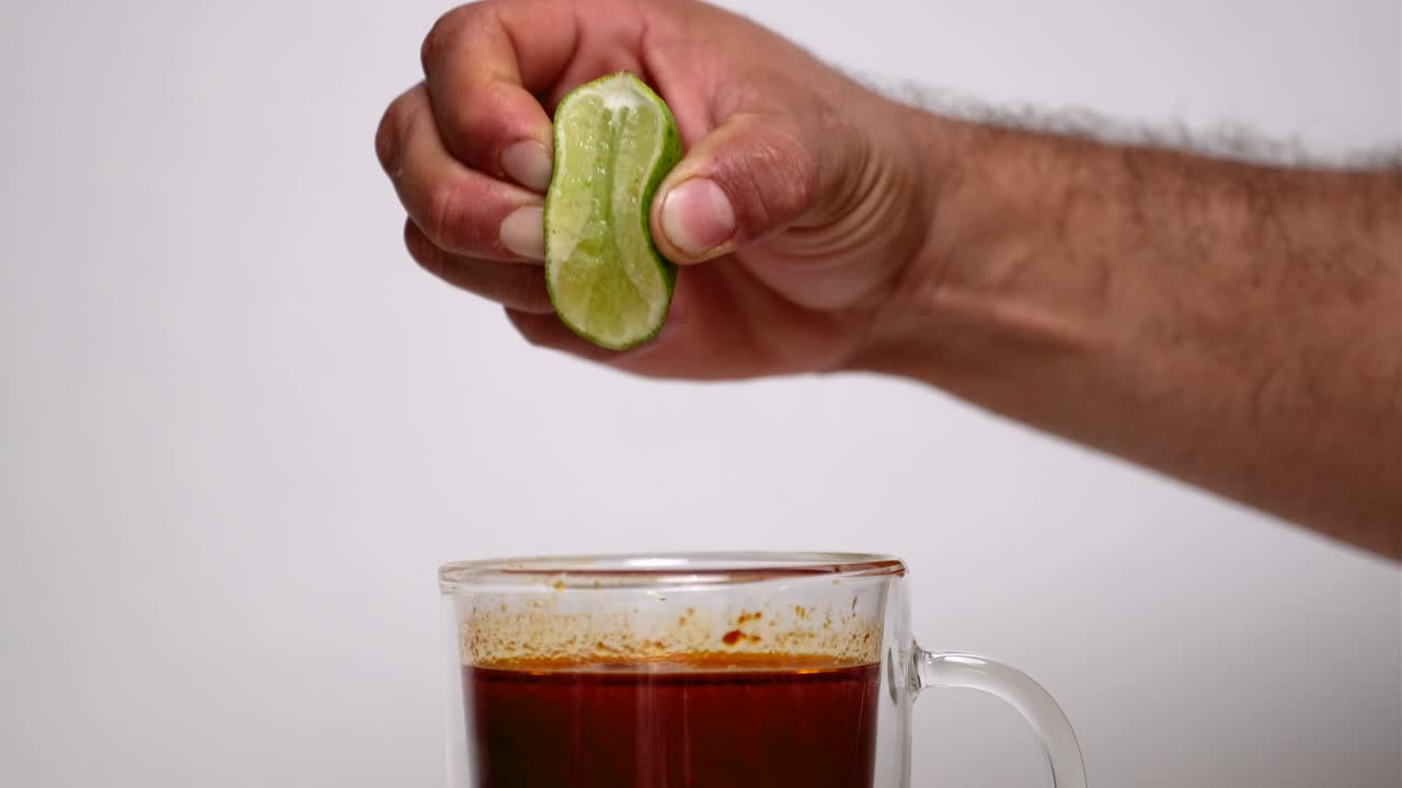 persona que exprime cal en una taza de consome birria