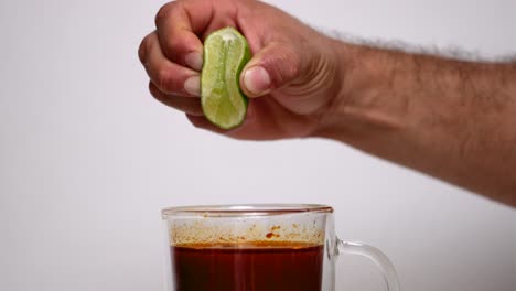 person squeezing lime into consome birria cup