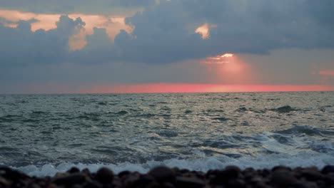 Waves-rolling-onto-rocky-beach-of-the-black-sea-during-the-sunset,-slow-motion