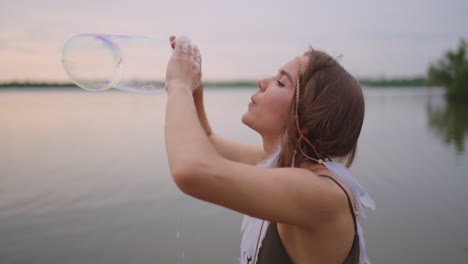 a young girl artist shows magic tricks using soap bubbles. create soap bubbles in your hands and inflate them location theatrical circus show at sunset