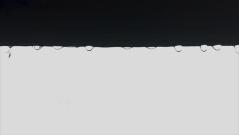 backlit slow motion raindrops falling off a window sill