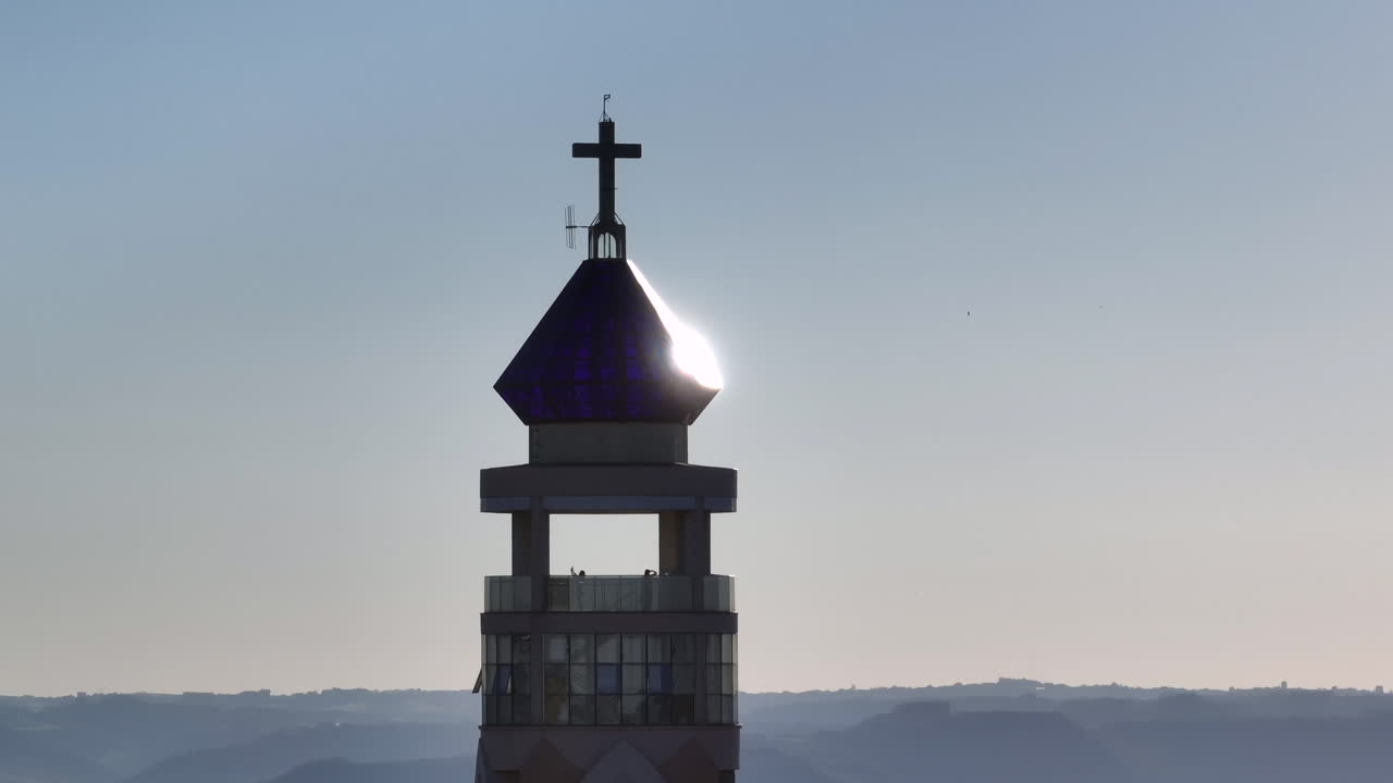Kostelní vyhlídková věž se otáčí v částečné rotaci, zatímco se sluneční světlo odráží na křišťálové kupoli a kříži nad obzorem