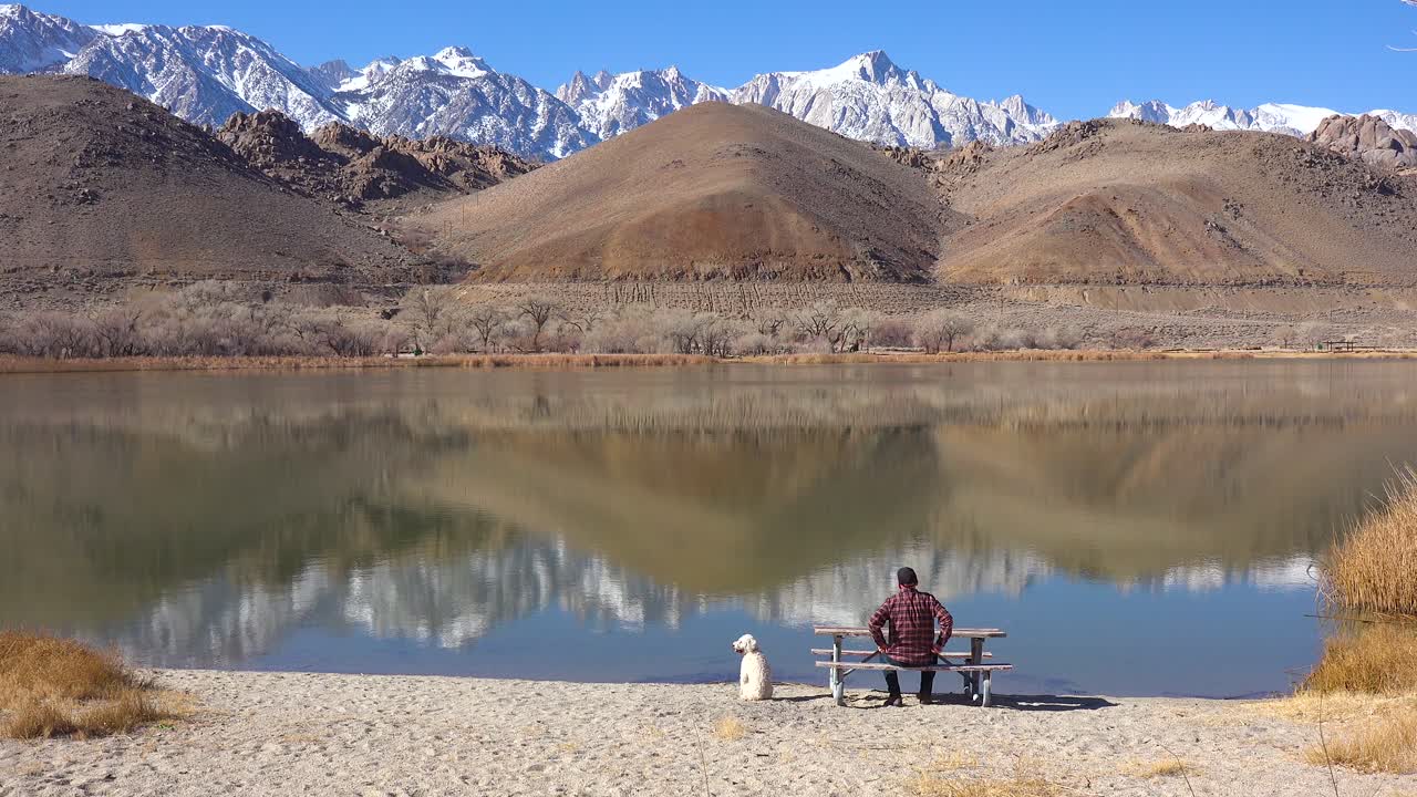 un hombre y su perro disfrutan de un hermoso día en un lago en la base de mt whitney y las montañas de sierra nevada cerca de lone pine california