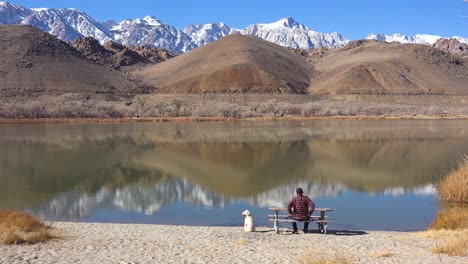 Un-Hombre-Y-Su-Perro-Disfrutan-De-Un-Hermoso-Día-En-Un-Lago-En-La-Base-Del-Monte-Whitney-Y-Las-Montañas-De-Sierra-Nevada-Cerca-De-Lone-Pine-California