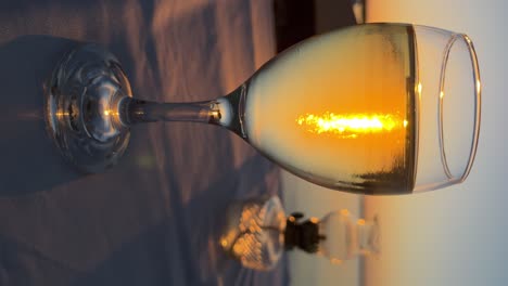 Glass-of-wine-in-the-foreground-and-vintage-table-oil-lamp-out-of-focus-against-sunset-backdrop