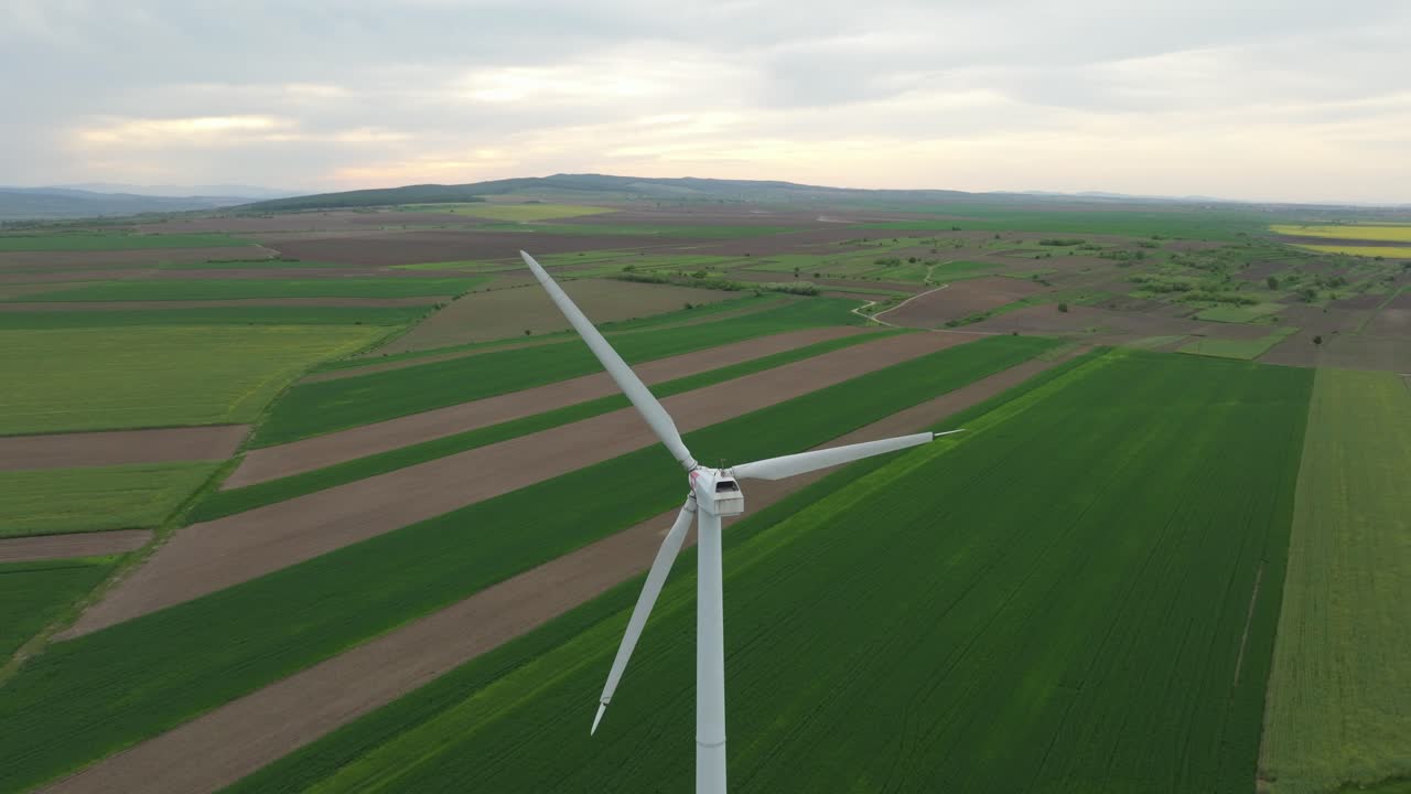 해가 뜨는 초록색 농장 위에 아오르는 에올리안 풍력 터빈