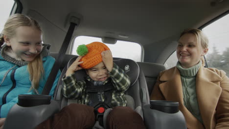 a cheerful family rides in the back seat of a car - a mother, a little child with a girl of ten years. have fun