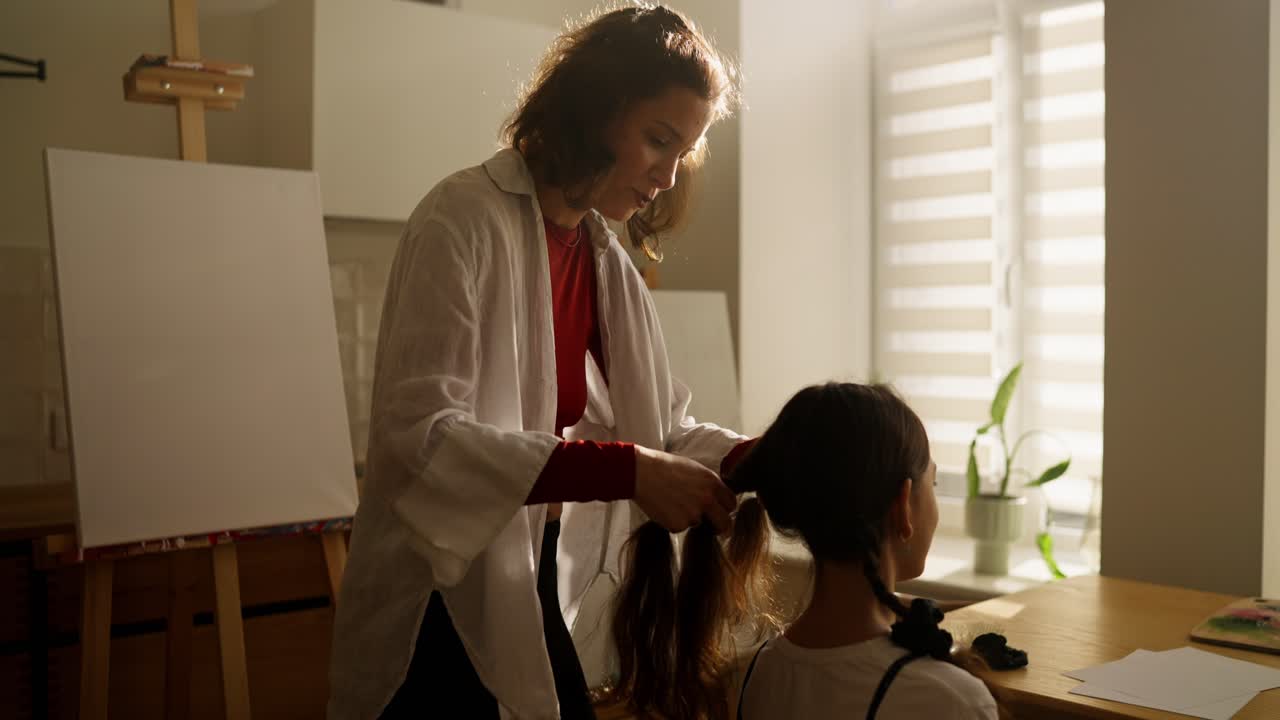 Madre trenzando el cabello de su hija en un estudio de arte