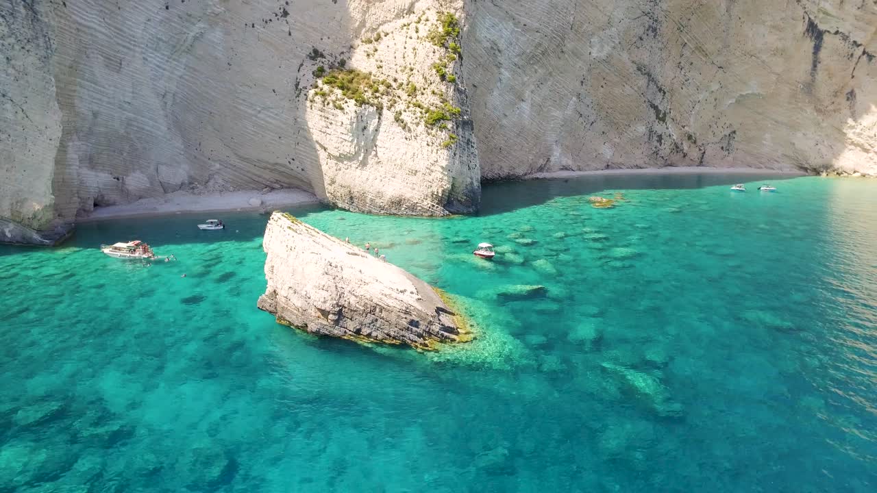 aguas cristalinas de color turquesa con una gran formación rocosa, playa oasi cerca de las cuevas de keri, zakynthos
