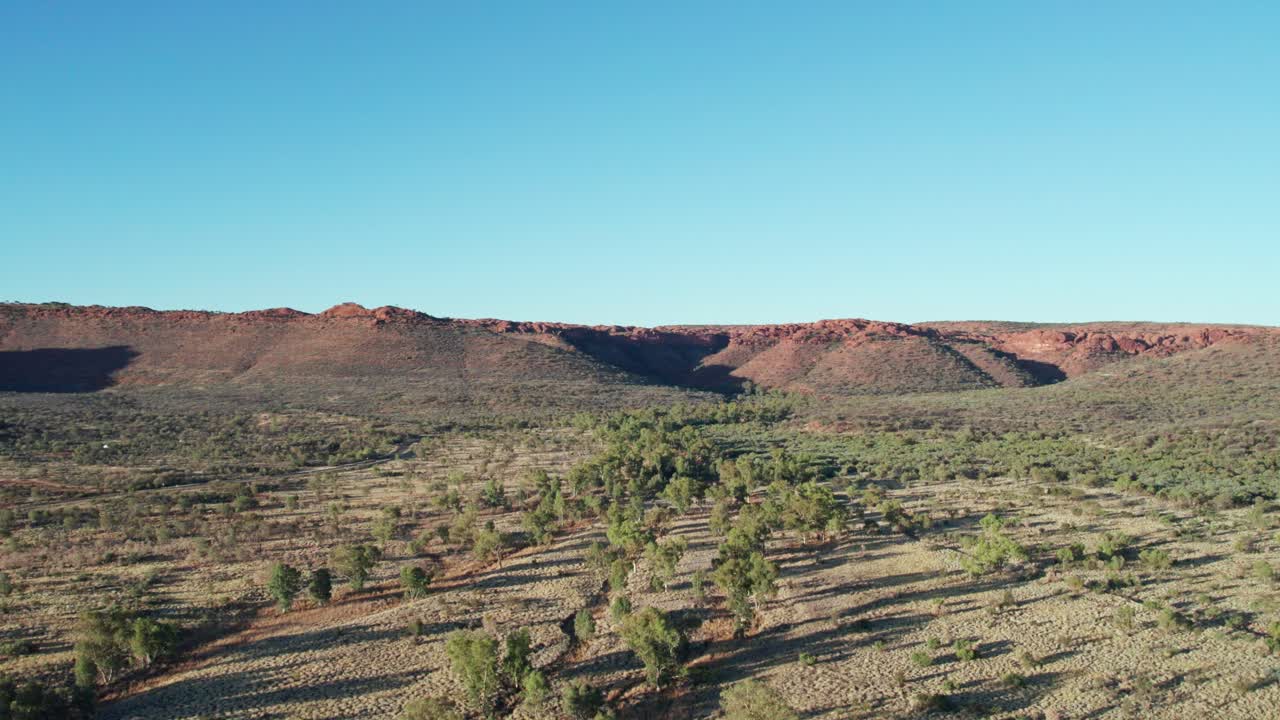 Rising drone footage of landscape with Kings Canyon, Watarrka in the distance, Northern Territory, Australia. August 2022.