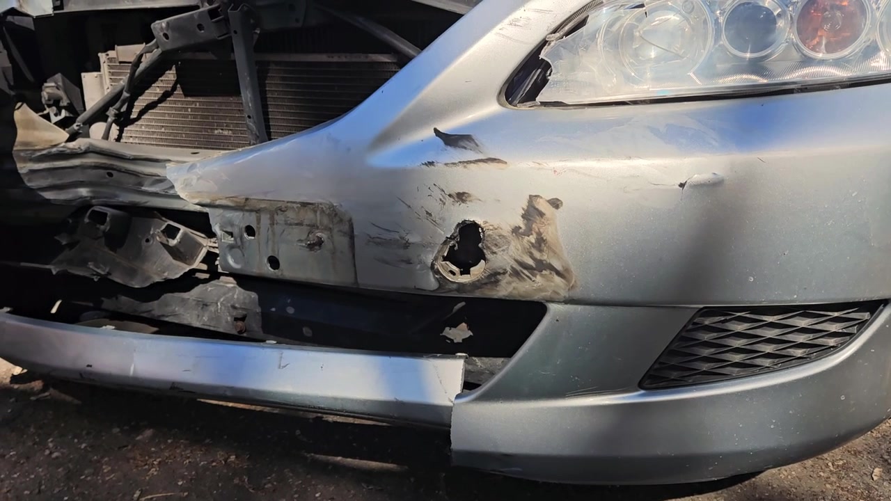 Schwenkaufnahme der total beschädigten Front eines Autos.